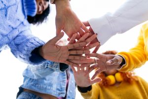 Group of young people joining hands together in a teamwork gesture